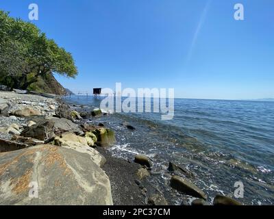 Verlassene hölzerne Pfahltürme Fischerhöhle am heimwerkerpier an der felsigen Küste des Fischerdorfes an sonnigen Sommertagen hellblauer Himmel Stockfoto