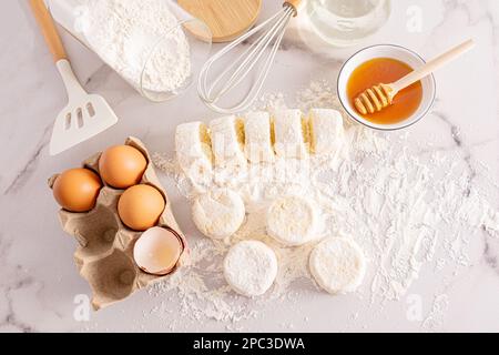 Viele verschiedene Zutaten für die Herstellung von Käsekuchen auf einer weißen Marmorplatte. Draufsicht. Gesundes Frühstück Stockfoto