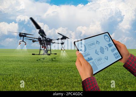 Der Landwirt steuert das Drohnenspray mit einem Tablet. Intelligente Landwirtschaft und Präzisionslandwirtschaft Stockfoto