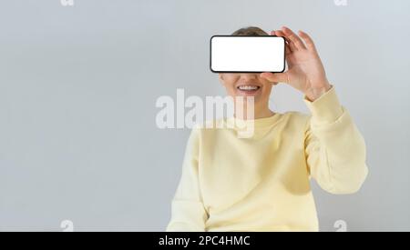 Eine Frau, die ein leeres Smartphone in der Hand hält. Stockfoto