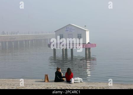 Freunde, die an einem nebligen Wintertag am Ufer von Baku sitzen Stockfoto