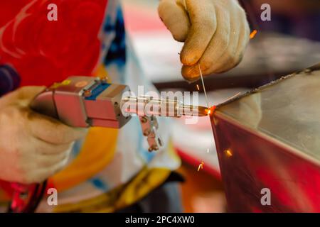 Schweißer Hände mit einem tragbaren Laserschweißgerät - Nahaufnahme Stockfoto