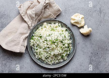 Roher Blumenkohl-Reis oder Couscous mit Dill in einer weißen Schüssel, gesunde kohlenhydratarme Gemüse-Beilage für Keto-Diät und gesunde kalorienarme Ernährung Stockfoto