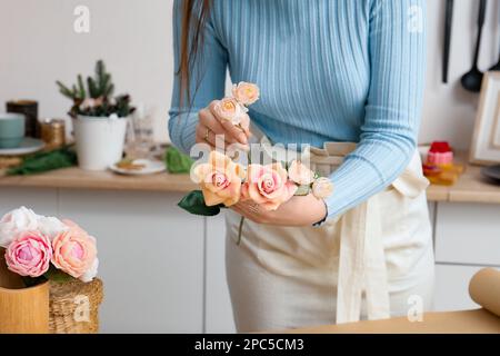 Die Blumenmeisterin macht einen Strauß. Seifenstrauß in den Händen eines Floristen. Rosen und Tulpen in den Händen eines Mädchens Stockfoto