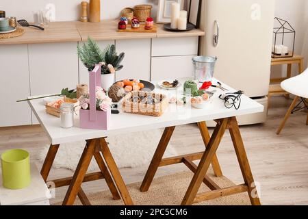 Die Seife liegt auf dem Tisch. Blumen, Fichtenäste, Mandarinen, Klebepistole, Eimer, Korb, Fäden, Zutaten für die Herstellung von Seifenprodukten. Stockfoto