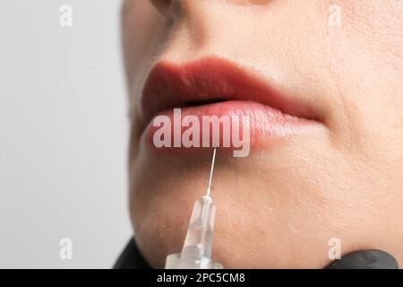 Schönheitsbehandlungen durch einen Kosmetiker aus nächster Nähe. Das Konzept der Verbesserung des Erscheinungsbildes. Lippenvergrößerung, Symmetrie, dicke Lippen. Neue Technik Stockfoto