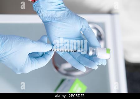 Spritze in den Händen eines Kosmetikers. Ästhetische Kosmetologie. Hände in blauen Handschuhen und eine Spritze mit einem medizinischen Präparat. Schönheitsspritzen. Botox. Stockfoto