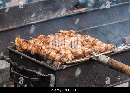 Schweinefleischspieß, gegrillt oder geröstet in einem Barbecue mit Mistgabeln an einem offenen Feuer und Flammen, Schaschlik oder Schaschlyk in einem Street Food Markt oder einem Outd Stockfoto