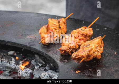 Zubereitung von Hähnchenspießen, gegrillt oder geröstet auf einem offenen Feuer mit Flammen, Schaschlik oder Schaschlyk für ein Picknick im Freien, Nahaufnahme Stockfoto