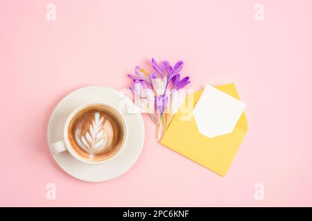 Kaffeetasse, Blumenstrauß und Umschlag mit leerer Karte. Draufsicht, flaches Lay, Modell. Stockfoto