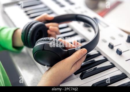 Nahaufnahme, schwarze Kopfhörer in den Händen eines Kindes, Musikkonzept. Stockfoto