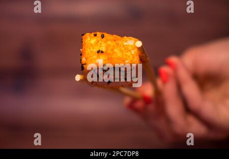 Sushi auf Stöcken in weiblichen Händen Nahaufnahme Stockfoto