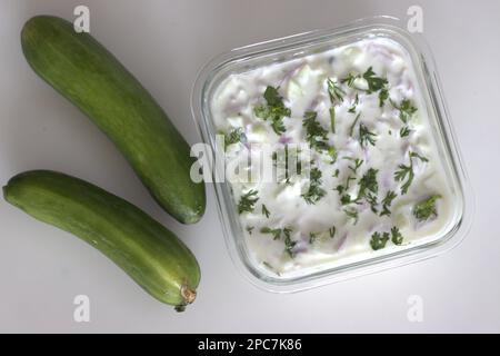 Gurkenraita. Fein gehackte Gurken und Zwiebeln in dickem Joghurt, gewürzt mit grünen Chilis und garniert mit Korianderblättern. Beilage Rezept mit Witwe Stockfoto