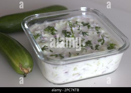 Gurkenraita. Fein gehackte Gurken und Zwiebeln in dickem Joghurt, gewürzt mit grünen Chilis und garniert mit Korianderblättern. Beilage Rezept mit Witwe Stockfoto