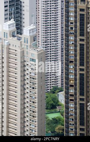 Blick auf den kleinen Garten und Tennisplatz zwischen den Wolkenkratzer-Apartmentblöcken in dicht besiedeltem Stadtgebiet, Hongkong, China Stockfoto