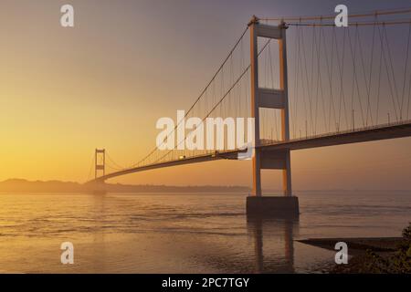 Blick auf die Hängebrücke bei Sonnenaufgang, Blick von Beachley in Richtung Monmouthshire Severn Bridge, River Severn, Severn Estuary, Gloucestershire Stockfoto