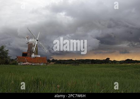 Blick auf das Küstengewölbe in Richtung Windmühle und Sturmwolken, Cley Windmill, Cley Marshes, Cley-next-the-Sea, Norfolk, England, Vereinigtes Königreich Stockfoto