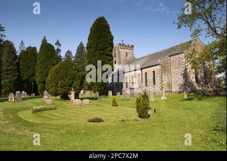 Blick auf Grabsteine und Eibenbäume im Friedhof der Pfarrkirche, St. Oswalds Kirche, Ravenstonedale, Westmorland, Cumbria, England, Vereinigtes Königreich, E Stockfoto