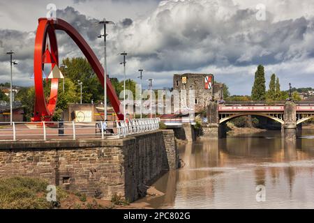 Blick auf eine Stahlskulptur am Ufer mit Schloss und Brücke im Hintergrund, „The Wave“, Newport Castle, Newport Bridge, Fluss Usk, Newport, Stockfoto