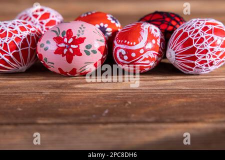 Ostereier in roten Schattierungen, die auf alten Brettern hintereinander angeordnet sind. Stockfoto