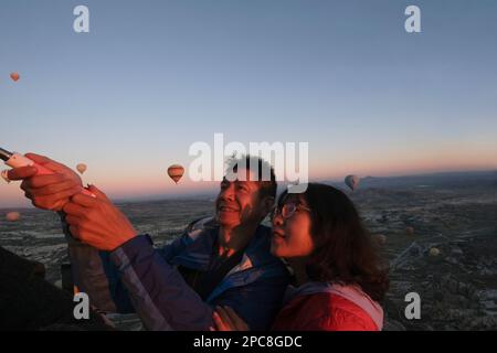 Touristen haben Spaß bei einem Flug mit Heißluftballons über die Berglandschaft bei Sonnenaufgang in Kappadokien, Goreme-Nationalpark, Türkei Stockfoto