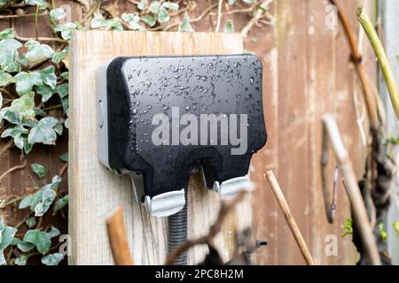 Flacher Fokus einer neu installierten, wetterfesten Doppelsteckdose in einem Garten. Stockfoto