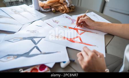 Eine gesichtslose Frau zeichnet Aquarelle von Sportbekleidung. Nahaufnahme der Hände eines Modedesigners. Stockfoto
