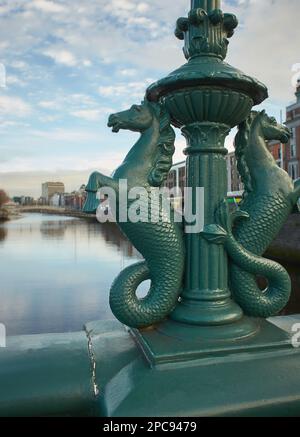 Bild des Flusses Liffey Dublin von der Grattan-Brücke mit der Zierstatue der Seepferdchen-Brücke im Vordergrund. Stockfoto