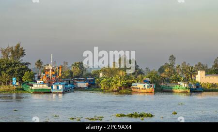 Boote und motorisierte Lastkähne liegen am Ufer des Mekong in der Nähe von Long Xuyen im Mekong-Delta, Vietnam. Stockfoto