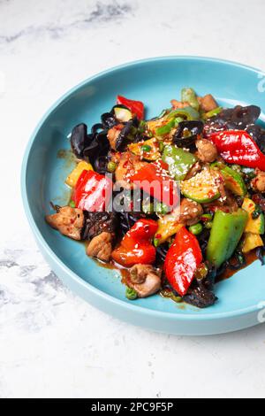 Draufsicht auf den schwarzen Lagman mit Huhn und Pfeffer auf einem blauen Teller. Stockfoto