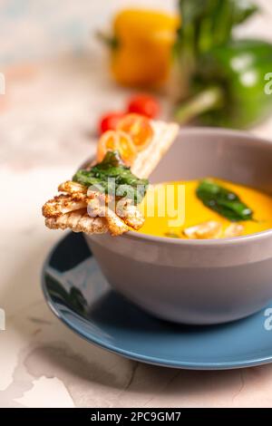 Leuchtend gelbe Kürbissuppe mit Samen auf einem Teller auf dem Tisch. Stockfoto