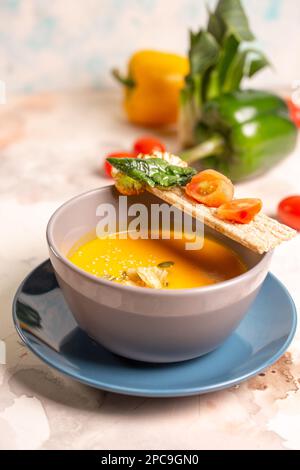 Leuchtend gelbe Kürbissuppe mit Samen auf einem Teller auf dem Tisch. Stockfoto