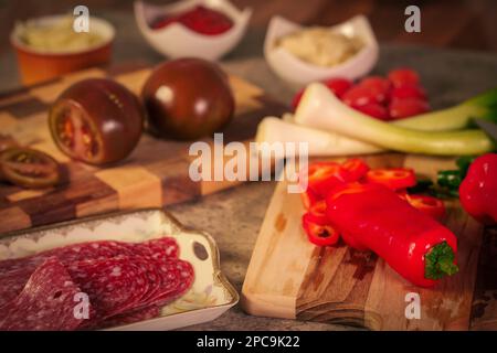 Eine Vielzahl von Speisen wie Fleisch und andere Zutaten auf Schneidebrettern vor der Pizza Stockfoto