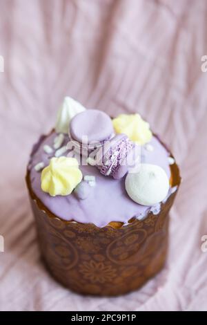 Ein traditioneller paska mit weißer Schweizer Schokolade und Baiser steht auf einer lavendelfarbenen Tischdecke. Osterferien Stockfoto