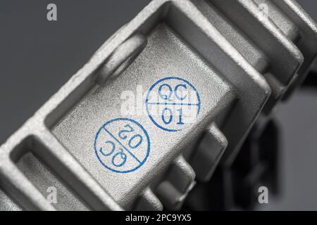 QC-/Qualitätskontrollstempel auf einem chinesischen DC/DC-Ladewandler aus Aluminiumdruckguss ohne Marke mit Wärmeleitflossen. Für gefertigte Elektrogeräte. Stockfoto