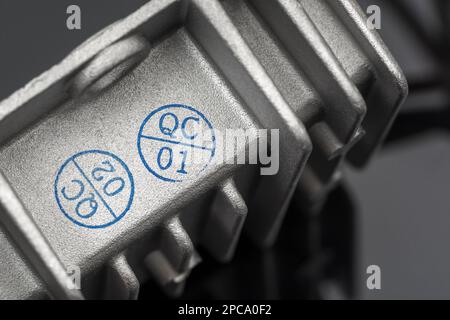 QC-/Qualitätskontrollstempel auf einem chinesischen DC/DC-Ladewandler aus Aluminiumdruckguss ohne Marke mit Wärmeleitflossen. Für gefertigte Elektrogeräte. Stockfoto