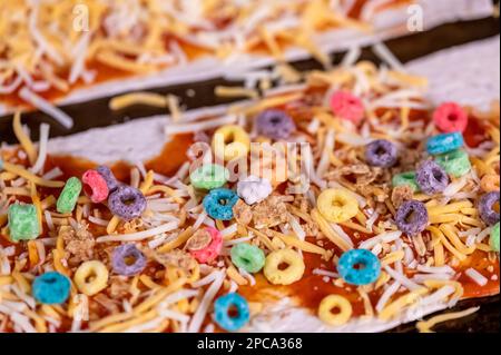 Pizza von einem Kind mit Müsli, Käse und Sauce. Stockfoto