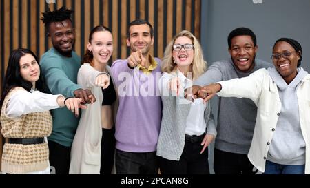 Eine Gruppe fröhlicher junger Leute, die nahe beieinander stehen und Sie zeigen Stockfoto