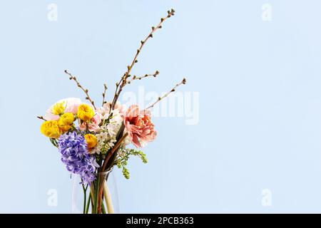 Ein strahlender Frühlingsstrauß aus Narzissen, Hyazinthen, Rosen, Ranunculus, Tulpen, Flieder und ein Zweig prunus. Hallo Frühling. Alles gute zum Geburtstag, alles gute zum Geburtstag Stockfoto