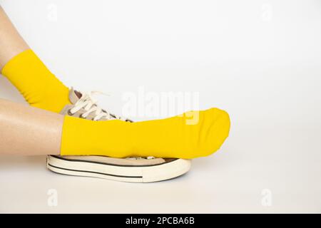 Damenbeine in gelben Socken und Sommersportschuhe auf weißem Hintergrund Stockfoto