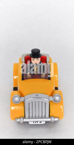 Sir Topham Hatt (der fette Controller) fährt ein gelbes Plastikauto aus der Thomas the Tank Engine Serie Stockfoto