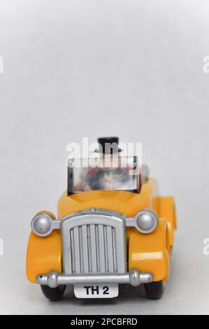 Sir Topham Hatt (der fette Controller) fährt ein gelbes Plastikauto aus der Thomas the Tank Engine Serie Stockfoto