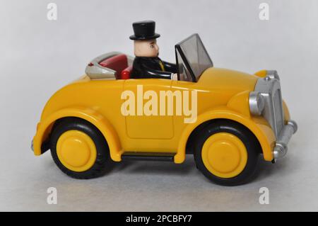 Sir Topham Hatt (der fette Controller) fährt ein gelbes Plastikauto aus der Thomas the Tank Engine Serie Stockfoto