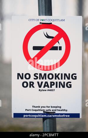 Rauchen verboten oder Dampf-Schild mit rotem kreisförmigem umgekehrtem Schrägstrich über einer brennenden Zigarette, die an einem Leuchtspfosten befestigt ist. Port Coquitlam, B.C., Kanada - vertikal. Stockfoto