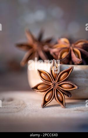 Anissterne (Illicium verum) in Holzschale auf dunklem rustikalem Holzhintergrund. Lieblingsspice in vielen Lebensmitteln und für die Medizin. Duftendes asiatisches Gewürz Stockfoto