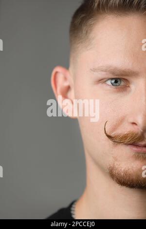 Halbporträt stylischer junger, gutaussehender Mann mit „Lenker“-Schnurrbart trägt ein legeres schwarzes T-Shirt und sieht selbstbewusst in die Kamera. Männliches Gesicht mit Stockfoto
