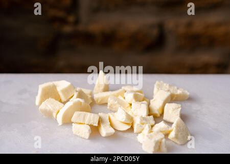 Mozzarella-Käse gewürfelt auf weißem Schneidebrett. Stockfoto