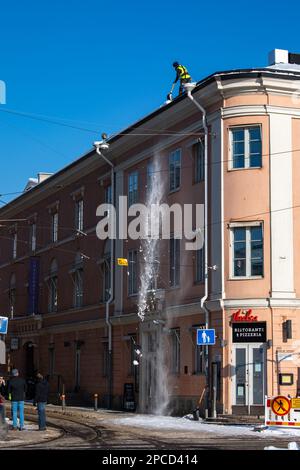 Dachschnee-Entfernung an einem sonnigen Wintertag im Stadtteil Kruununhaka in Helsinki, Finnland Stockfoto