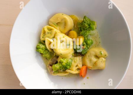 Gekochte Tortellini in White Bowl. Agnolotti, Cappelletti, Teigtaschen, Gefüllte Pasta, Tortelloni, Ravioli, Cappelletti, Uszka mit Romanesco, Pilze A. Stockfoto