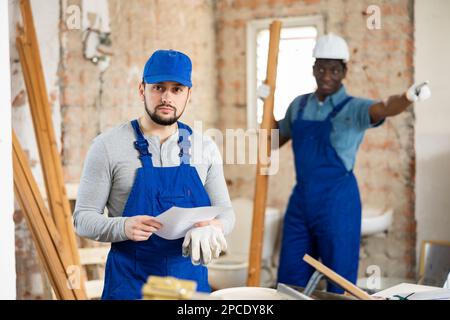 Vorarbeiter unzufrieden mit der Qualität der Reparaturarbeiten des männlichen Bauherrn Stockfoto